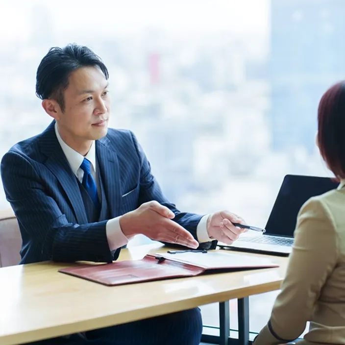 スーツを着た男性が、お客様に資産運用の支援をしている様子